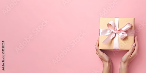 Gift in female hands on a colored background top view. Female hands hold gift box. Copy space for design