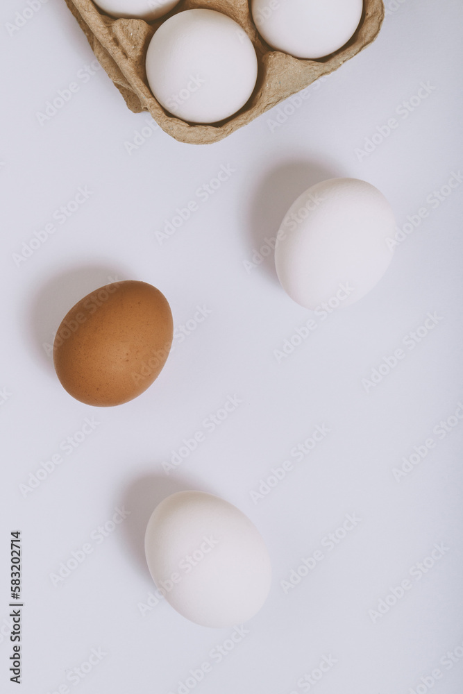 White and brown eggs on bright background and white eggs in brown egg tray. Selective focus. Concept scene. Top view. 