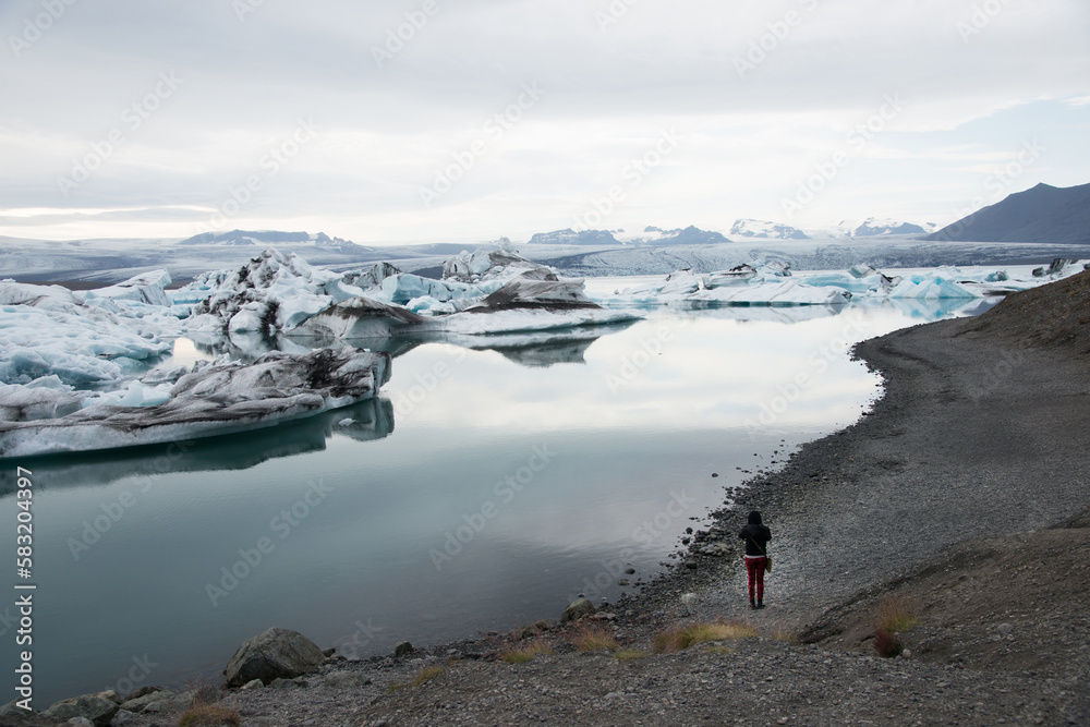 Woman seen from her back taking a piceture at Jokulsarlon glacier Woman seen from her back taking a piceture at Jokulsarlon glacier