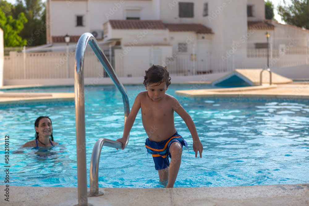 child climbing out of the pool by the stairs