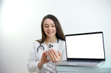 friendly female doctor over white background with a laptop. woman doctor working on the phone answering the call in front of her laptop with white screen space for advertising High quality photo