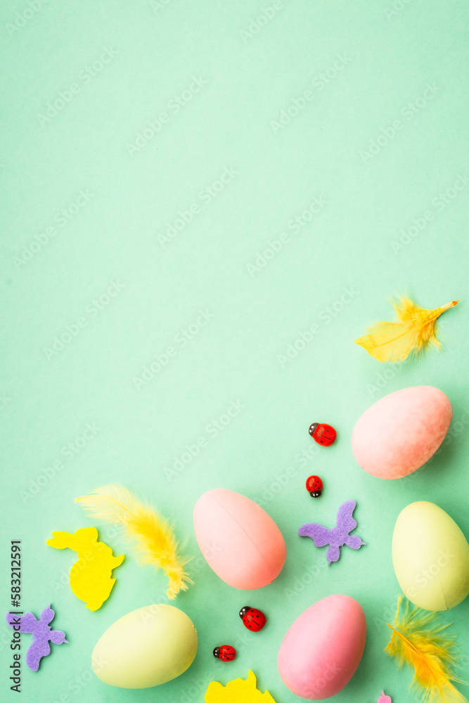 Easter background. Eggs, rabbit, spring flowers and butterfly. Flat lay mock up at green background.
