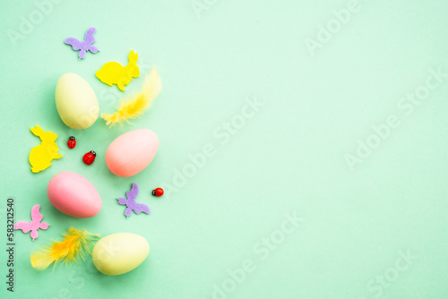 Easter background. Eggs  rabbit  spring flowers and butterfly. Flat lay mock up at green background.