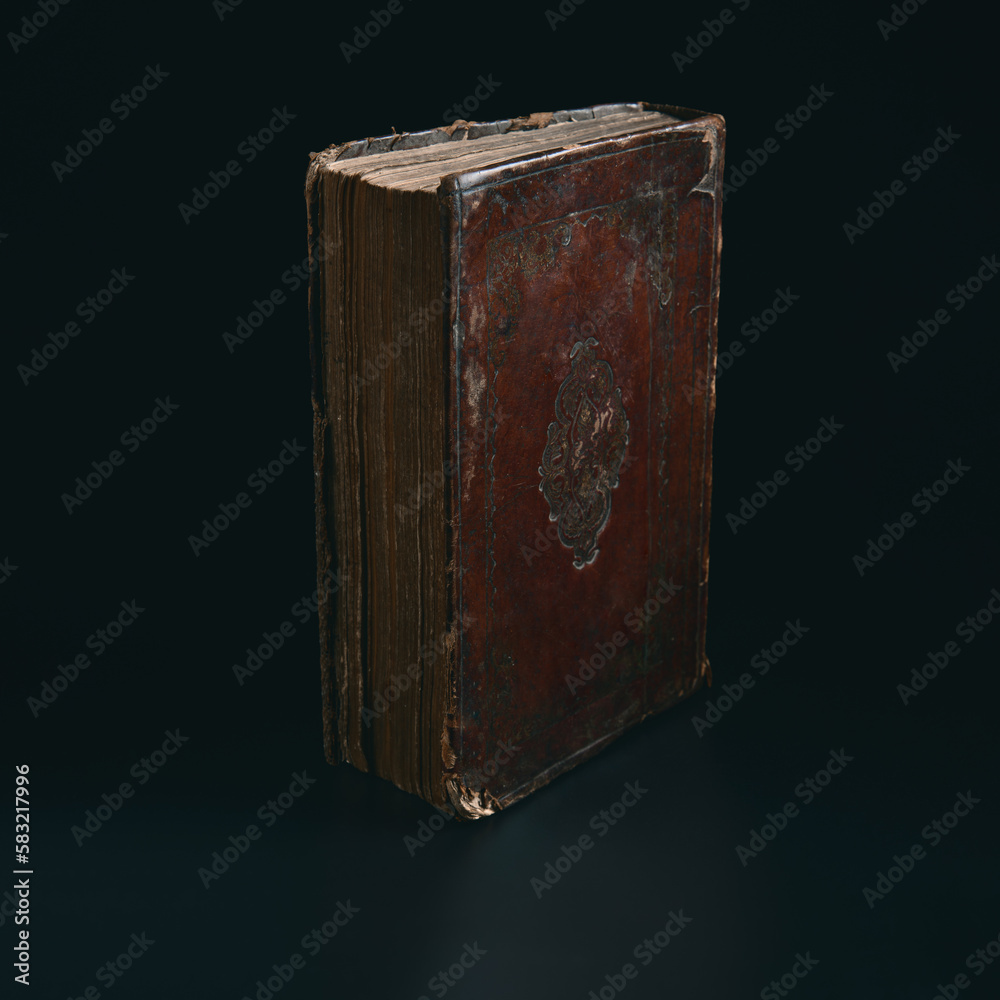 Leather bound book with gold embossing. Torah book standing in the dark. Education and religion concept. Low key. Closeup.