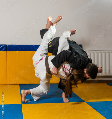 Young girl and boy practice Brazilian jiu jitsu in the gym