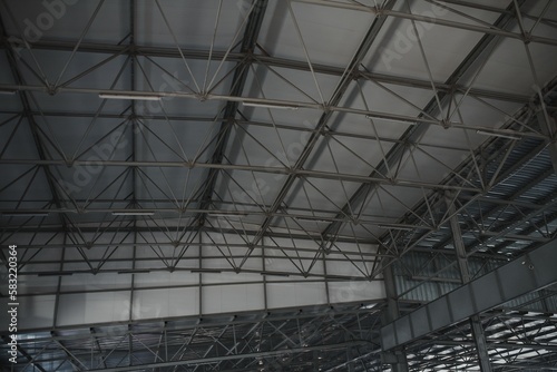 Steel roof structure for building construction. Metal roof structure of a building under construction on a blue sky background with white clouds. Selective focus