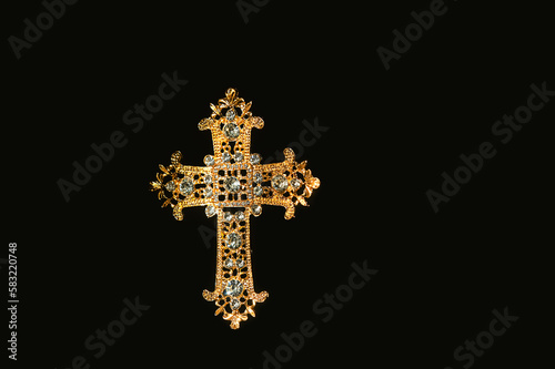 openwork decorated beautiful golden cross with rhinestones isolated on abstract black background close up. Cross - symbol of prayer, memory, Lent, Easter, Faith in God. element for design. flat lay