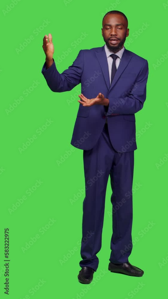 Vertical video: Front view of male entrepreneur creating advertisement on camera, talking about something on left or right sides. Professional company manager doing ad presentation over full body Vertical video: Front view of male entrepreneur creating advertisement on camera, talking about something on left or right sides. Professional company manager doing ad presentation over full body