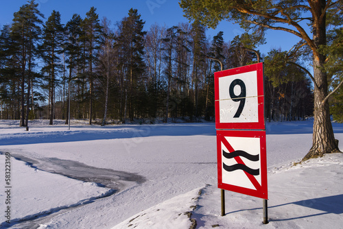 Speed limit and prohibition of causing waves sign next to a frozen river photo