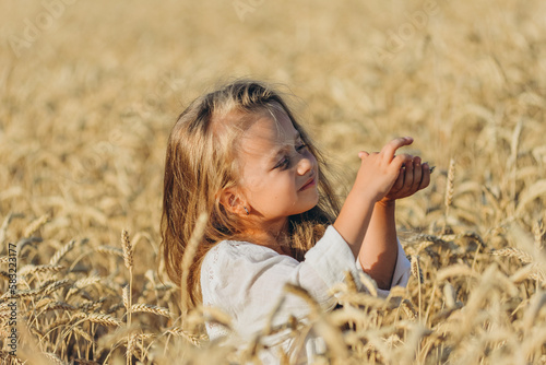 Growing wheat. Food security. A little blonde girl stands in a wheat field in summer.
