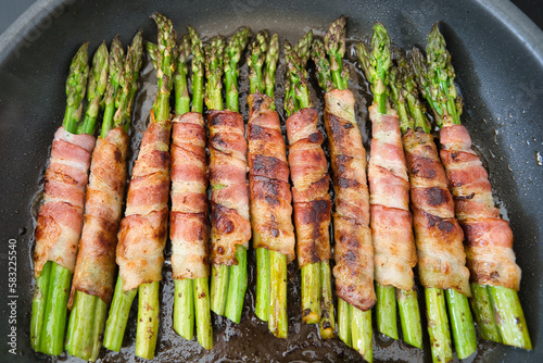 Viele Bündel grüner Spargel im Speckmantel in der Pfanne