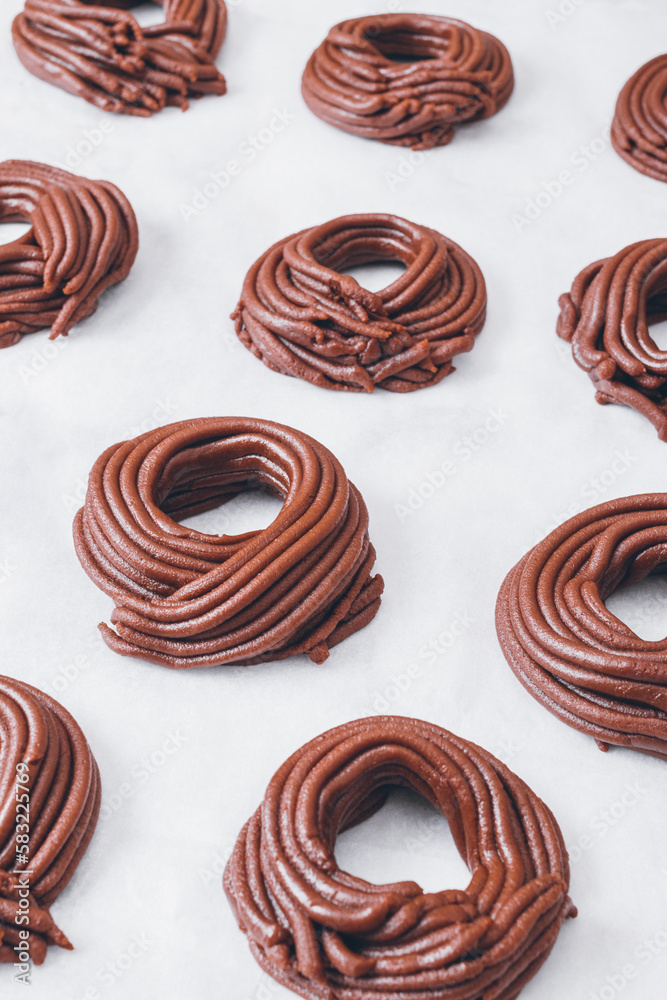 Cacao dough for cookies, dough in the shape of a circle or a nest on parchment paper. Preparing process to baking. Cacao dough for cookies, dough in the shape of a circle or a nest on parchment paper. Preparing process to baking.