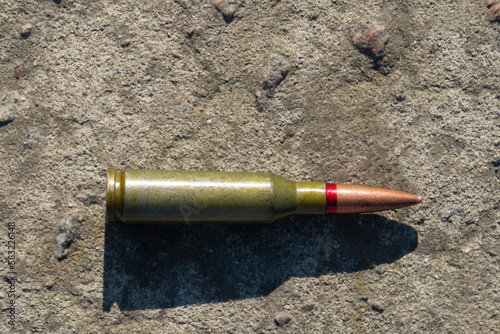 A rifle cartridge lies on a concrete surface (close-up). Horizontal orientation