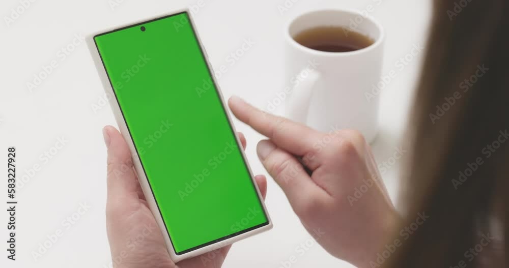 Woman with green screen smartphone scrolling through social media or online shop Woman with green screen smartphone scrolling through social media or online shop