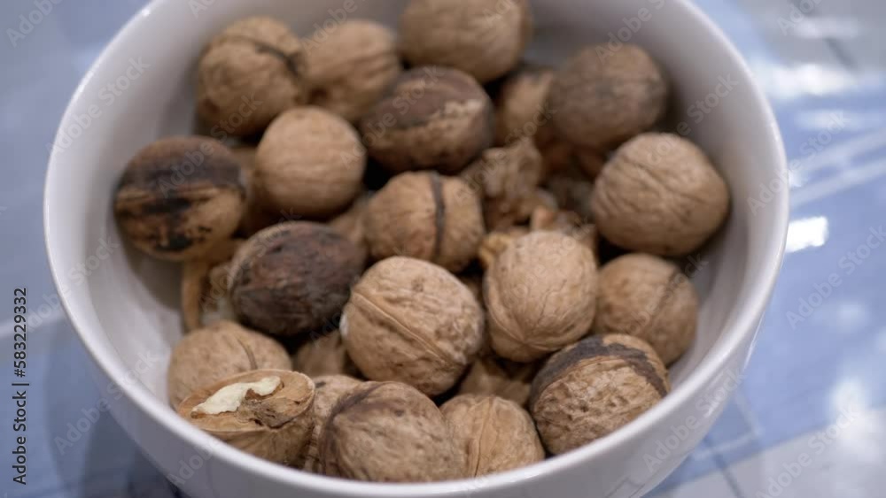 Farmer's Hand Taking One Walnut from a Full Bowl of Harvested Nuts. Close-up. Autumn harvest of ripe, fresh walnuts. Useful healthy food. Brain food. Diet food. Vegetarianism. Walnut shell. 4K. Farmer's Hand Taking One Walnut from a Full Bowl of Harvested Nuts. Close-up. Autumn harvest of ripe, fresh walnuts. Useful healthy food. Brain food. Diet food. Vegetarianism. Walnut shell. 4K.