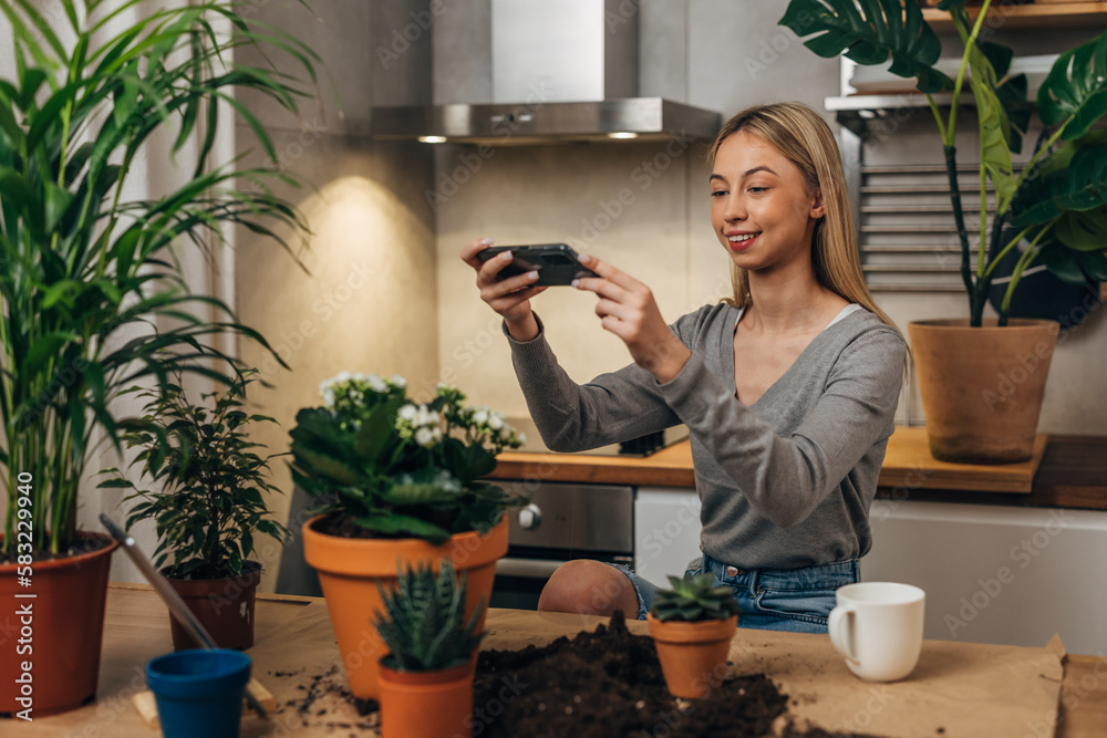 A beautiful Caucasian girl is taking photos of her houseplants A beautiful Caucasian girl is taking photos of her houseplants