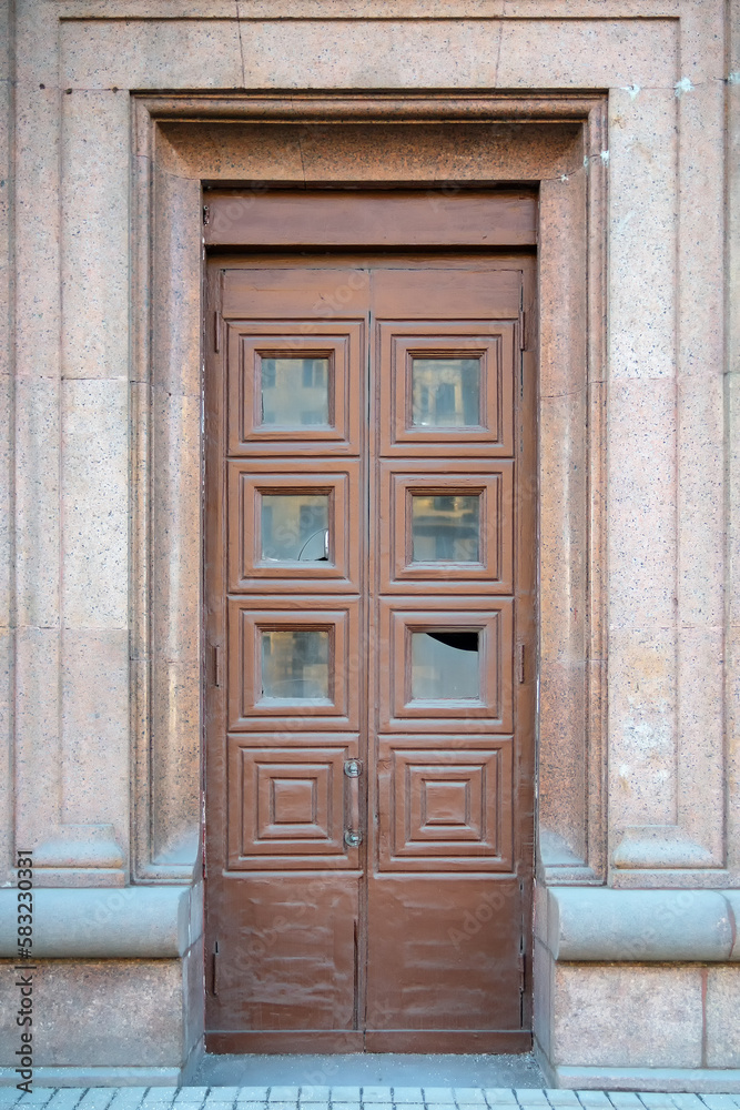 Tall old wooden door with square ornament and broken glass Tall old wooden door with square ornament and broken glass