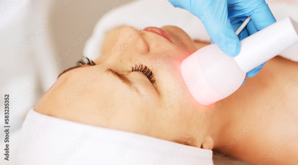 Naklejka premium eautician cosmetologist doing facial skin procedure with electroporation device in a beauty clinic salon for client. Skincare and machine cosmetology spa concept. 