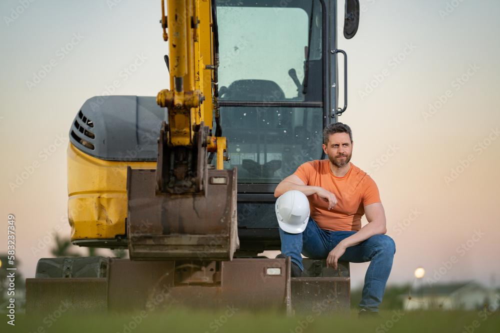 Portrait of worker man small business owner. Construction worker with hardhat helmet on construction site. Construction engineer worker in builder uniform with excavation truck digging. Worker