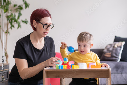  cheerful boy living with down syndrome play games in physical therapy rehabilitation room