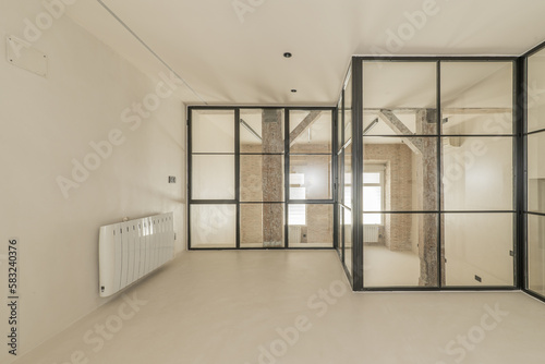 Modern loft apartment with old wooden beams and pillars  exposed brick walls  black metal framed glass partitions with one window  smooth white concrete floors