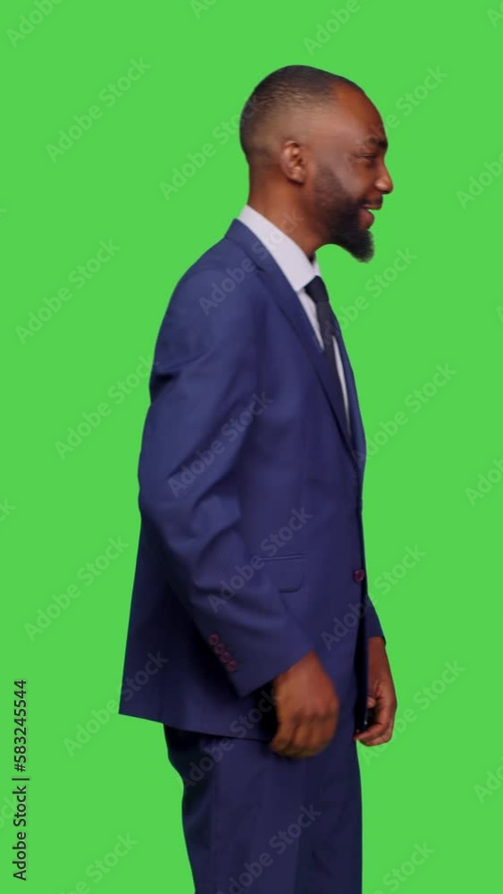Vertical video: Side view of corporate manager in suit asking someone to come over, calling over people to join standing over greenscreen backdrop. Young man working as businessman and feeling Vertical video: Side view of corporate manager in suit asking someone to come over, calling over people to join standing over greenscreen backdrop. Young man working as businessman and feeling