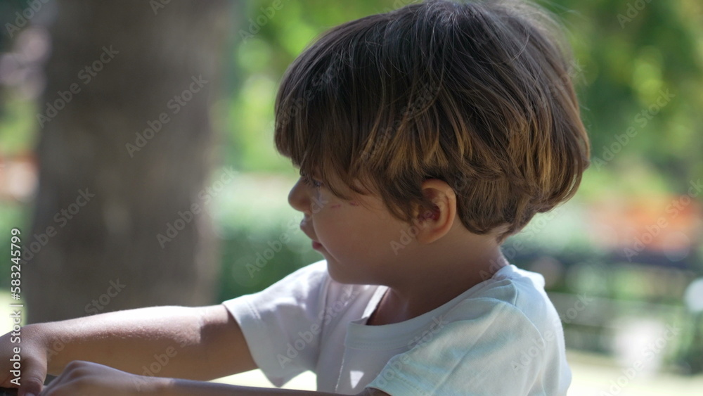 One small boy playing at playground carousel turning around. Kid in roundabout fun outside during sunny day One small boy playing at playground carousel turning around. Kid in roundabout fun outside during sunny day