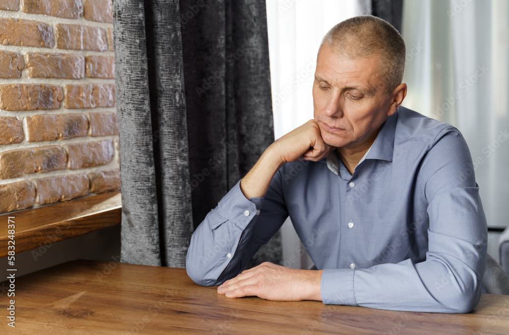 Portrait of a pensive middle-aged man sitting at a table. Portrait of a pensive middle-aged man sitting at a table.