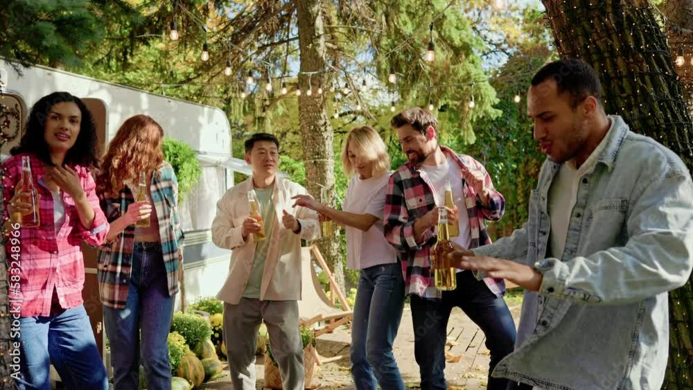 Mixed-race party of friends with beer in their hands. Have fun listening to music and dancing at festive summer parties near the travel trailer. Happy multi ethnic young people. Mixed-race party of friends with beer in their hands. Have fun listening to music and dancing at festive summer parties near the travel trailer. Happy multi ethnic young people.