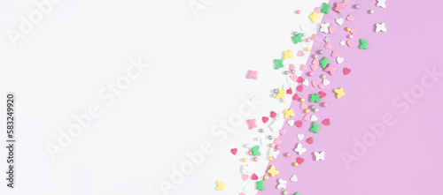Easter composition, banner.Top view on colorful sugar candy sprinkles isolated on white and pastel lilac background. Easter concept. Flat lay, top view, copy space 