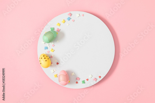 Easter celebration composition. Top view of blank white circle, easter eggs and colorful sugar candy sprinkles isolated on pastel pink background. Easter concept. Flat lay, top view, copy space 