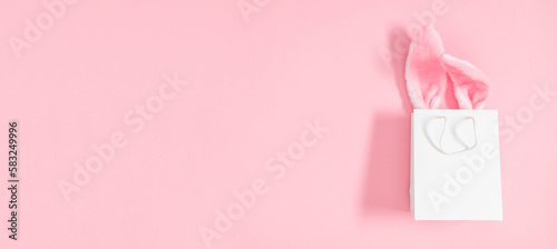 Easter market background, banner. Gift bag with bunny on pink table background. Top view of fluffy easter bunny ears. Concept of online shopping for Easter. Flat lay, top view, copy space © prime1001