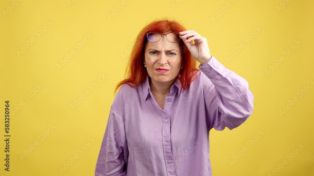 Aged redheaded woman taking off her glasses to see Aged redheaded woman taking off her glasses to see
