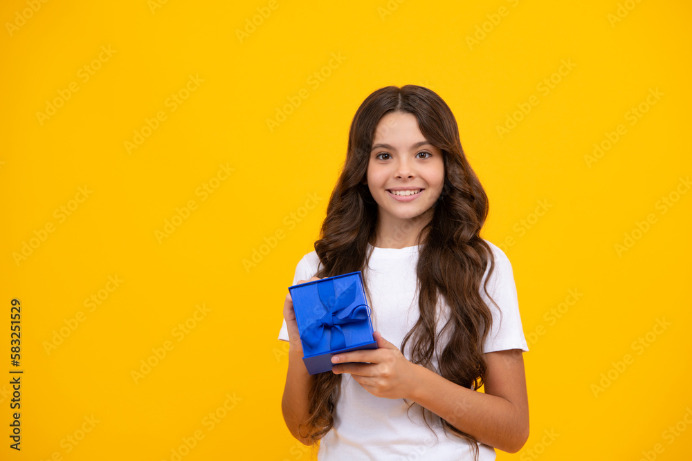 Portrait of a teenager child girl holding present box isolated over yellow studio background. Present, greeting and gifting concept. Birthday holiday concept. Portrait of a teenager child girl holding present box isolated over yellow studio background. Present, greeting and gifting concept. Birthday holiday concept.