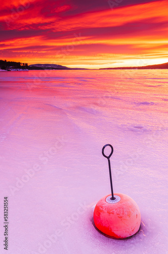 Bouy in frozen lake at sunrise photo