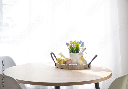 Canvas Print Easter decoration of colorful eggs, fresh grass in a watering can, easter bunny on a tray on the round table in a rustic style