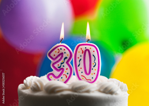Number 30 Birthday Candles Against Colorful Balloon Background photo