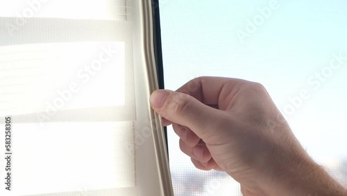 The man wipes the window frame with a degreaser and glues a sealing rubber tape on it for noise insulation, wind protection, weather protection.