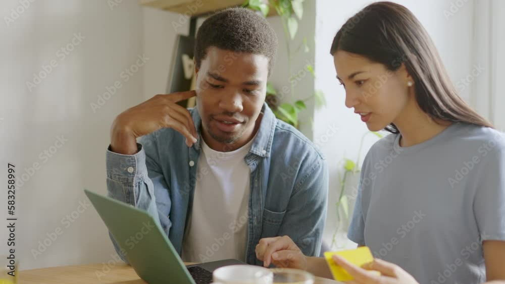 Doubtful multiethnic couple about to shopping online from home Doubtful multiethnic couple about to shopping online from home