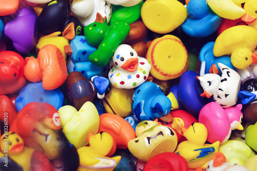 Top view of various colorful bath rubber plastic ducks. One duck facing and looking at camera. Design element. Uniqueness and leadership concept. © VisualArtStudio