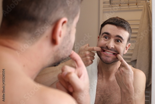 Man forcing a smile in the bathroom mirror 