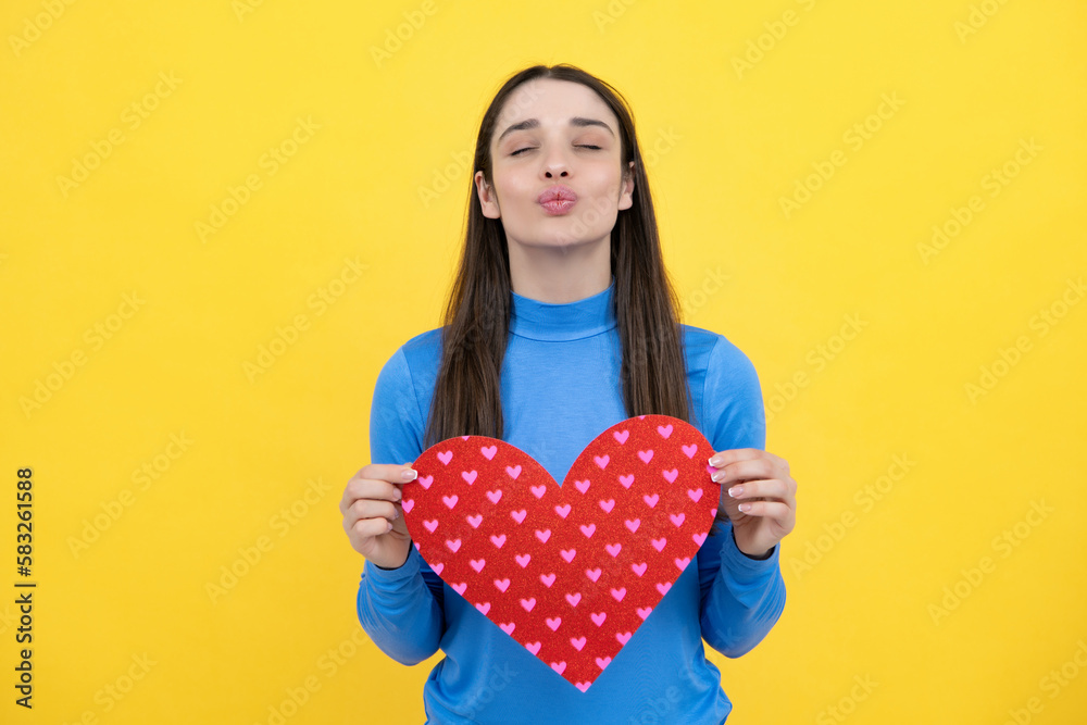 Portrait of attractive lovely cheerful girl holding in hands paper heart, isolated over yellow background. Love valentine concept. Portrait of attractive lovely cheerful girl holding in hands paper heart, isolated over yellow background. Love valentine concept.