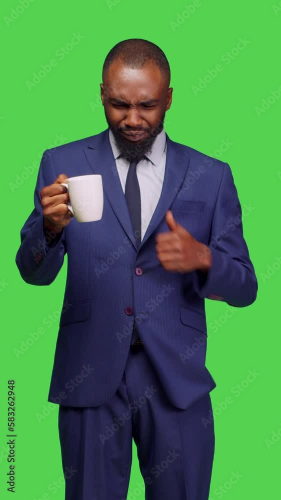 Vertical video: Front view of company employee drinking cup of coffee on camera, posing with confidence over green screen background. Male startup manager enjoying caffeine beverage or refreshment Vertical video: Front view of company employee drinking cup of coffee on camera, posing with confidence over green screen background. Male startup manager enjoying caffeine beverage or refreshment