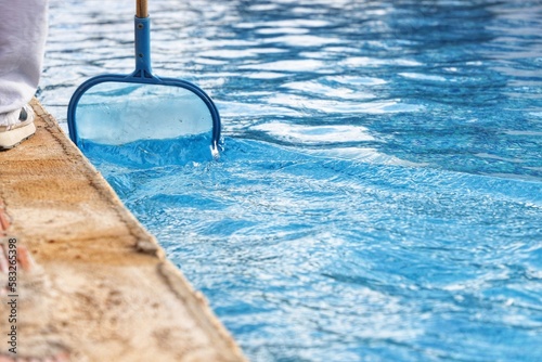 Primer plano de persona limpiando la piscina con mosquitera, preparándola para verano