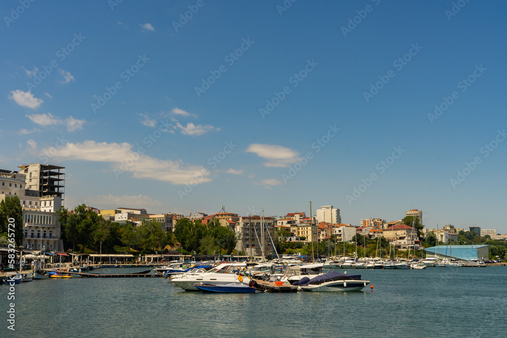 Motor boats and yachts are docked in the port, near the pedestrian promenade