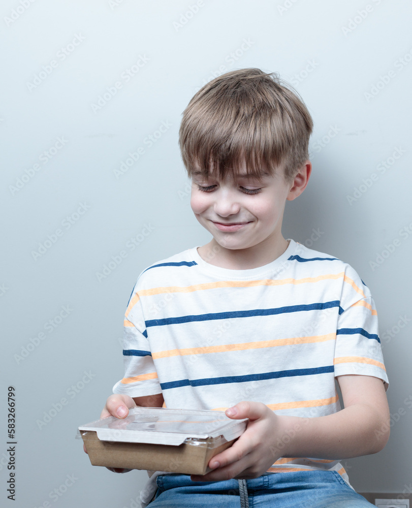 Blond-haired boy with a container of ready-made food. Food delivery, ready meals