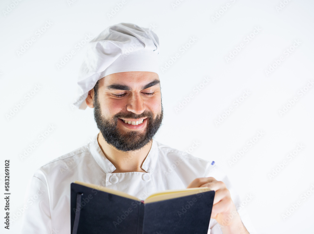 Young male chef using a notebook, writing a recipe. Isolated on a white background