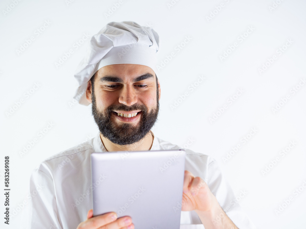 Young male chef using a tablet, reading a recipe. Isolated on a white background Young male chef using a tablet, reading a recipe. Isolated on a white background