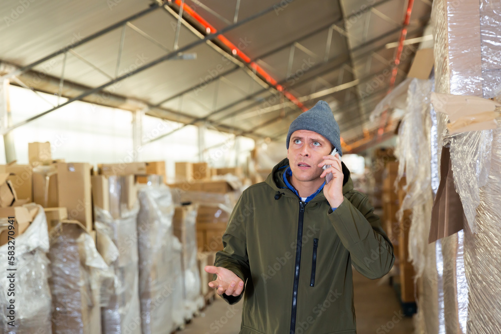 Male warehouse worker talking on a cell phone