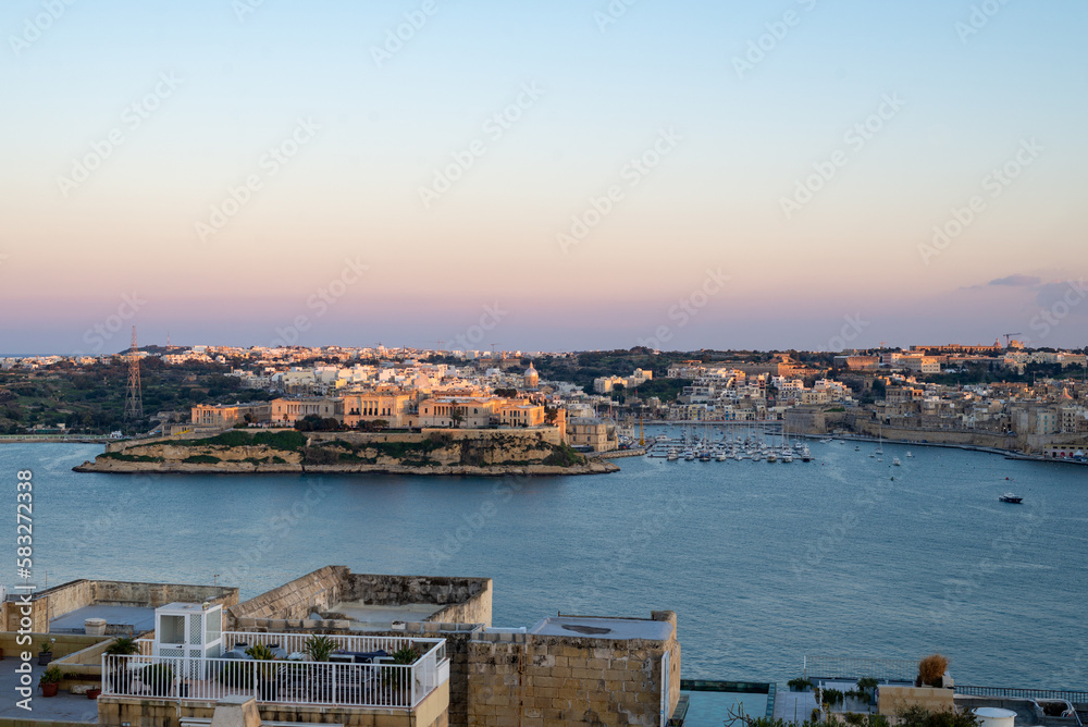 Sunset in Valetta with a view on The Three Cities. View on the city and the sea from a rooftop terrace
